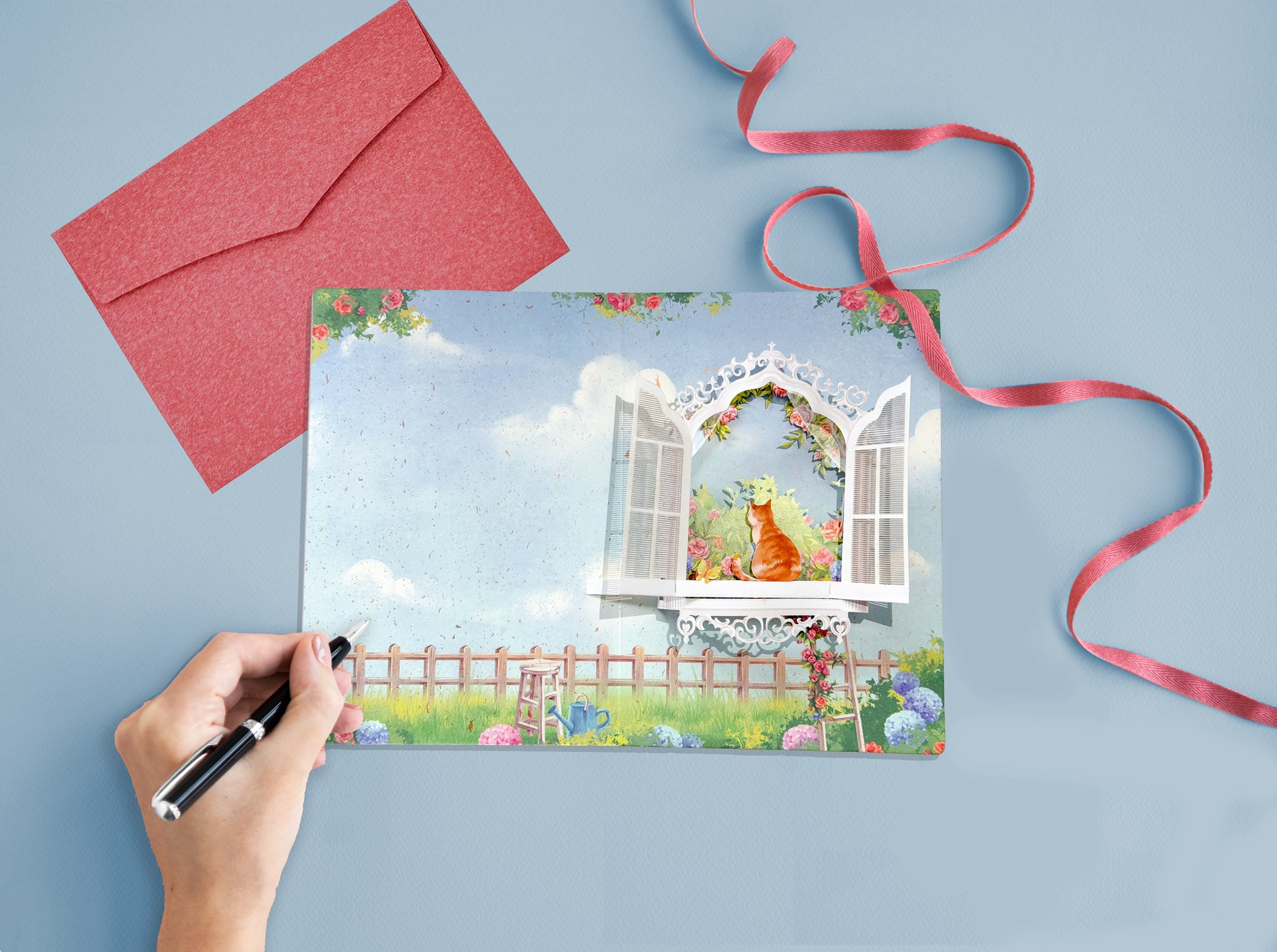Greeting card with a yellow cat in a window, red envelope, and ribbon on a blue background